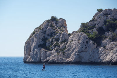 Rock formation in sea against clear sky