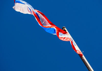 Low angle view of flag against clear blue sky