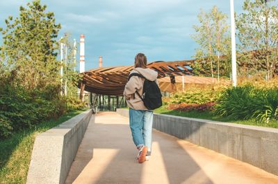 Rear view of woman on footpath against sky