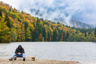 Rear view of woman sitting on lake