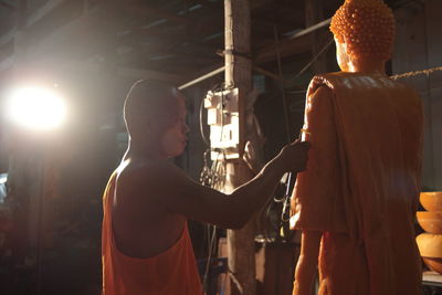 Rear view of man standing by illuminated lighting equipment