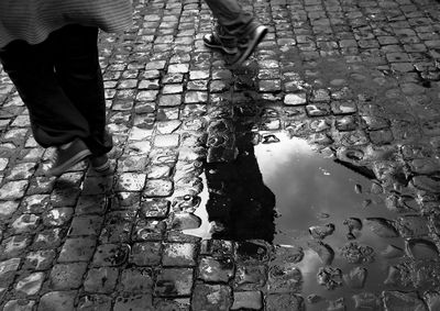 Low section of man and woman walking on wet footpath