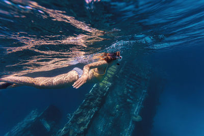 Woman swimming near shipwreck in sea