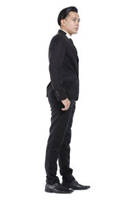 Side view of young man standing against white background