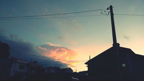 Low angle view of silhouette electricity pylon against sky