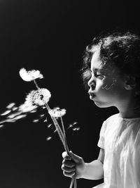 Portrait of cute girl holding sparkler against black background