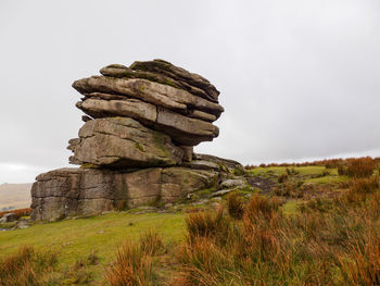 Tor rock formation among the moor  shrubs overlooking the hills of dartmoor. devon, united kingdom.