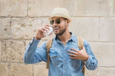 Young man wearing hat standing against wall