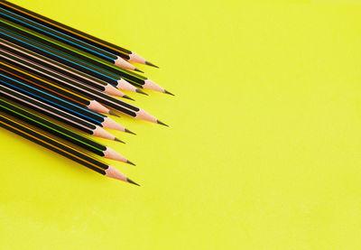 Close-up of colored pencils against yellow background