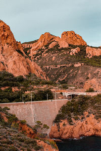 Scenic view of dam by rocky mountains against clear sky