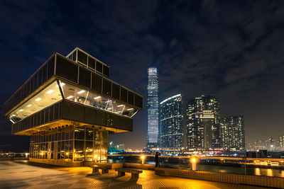 Illuminated modern buildings in city against sky at night