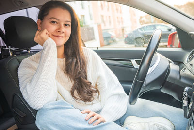 Portrait of young woman sitting in car