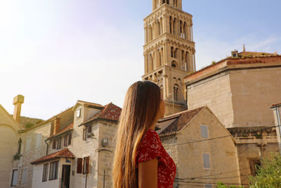 Side view of woman standing against buildings in town