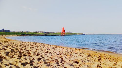 Lighthouse by sea against sky