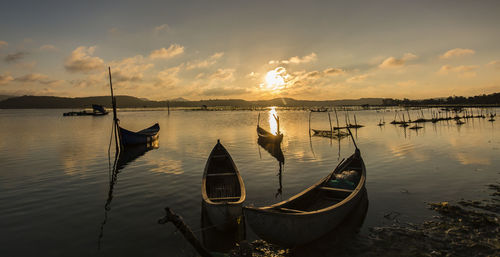 Sailboats moored on sea against sky during sunset