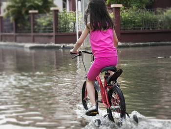 Rear view of boy with bicycle in water