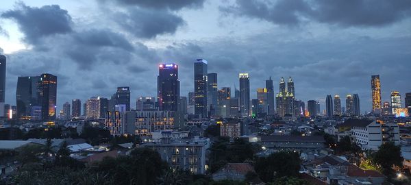 Illuminated cityscape against cloudy sky in early evening in jakarta