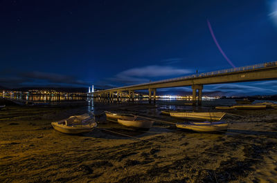 Illuminated bridge over sea against sky at night