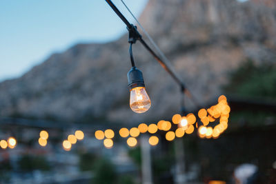 Low angle view of illuminated light bulb against sky