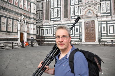 Portrait of man holding camera in city