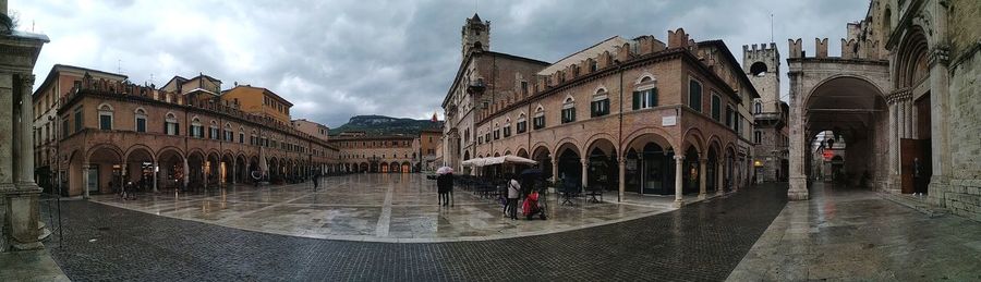 Panoramic view of wet street amidst buildings against sky