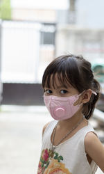Portrait of cute girl wearing mask while standing outdoors