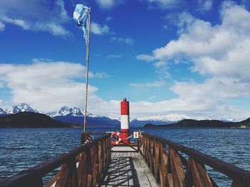 Pier on sea against cloudy sky