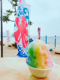 Close-up of drink on table by sea against sky