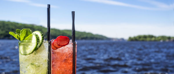 Close-up of drinks on water against sky