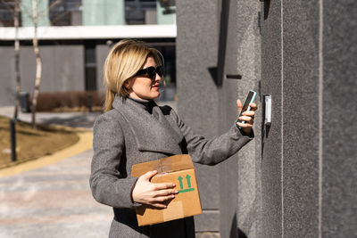 Young woman wearing sunglasses while standing against building