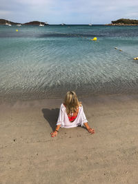 Rear view of woman sitting on beach