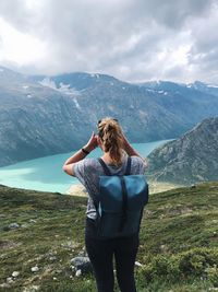 Rear view of woman with backpack standing on mountain against sky
