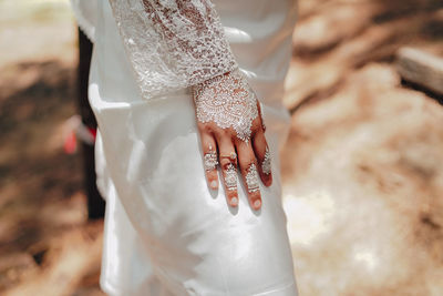Midsection of bride wearing wedding dress while standing outdoors