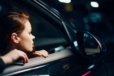 Side view of young woman sitting in car