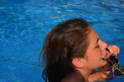 Side view of woman wearing sunglasses while swimming in pool