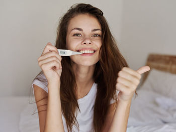 Portrait of smiling young woman sitting on bed at home