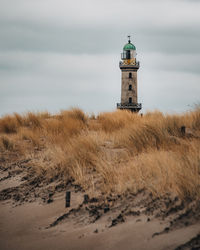 Lighthouse by sea against sky