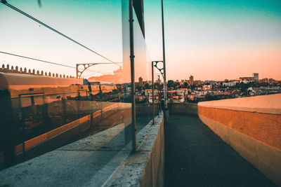 City street by buildings against sky during sunset