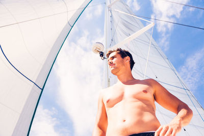 Low angle view of man standing in sea against sky