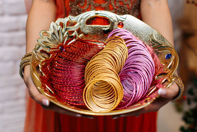 Midsection of woman holding tray with bangles