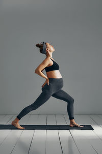 Low section of woman exercising against gray background