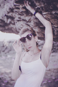 Portrait of beautiful woman holding sunglasses while standing outdoors