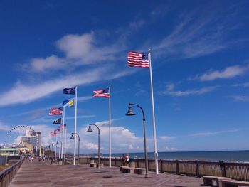 Flag on pole by sea against blue sky