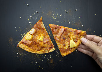 Close-up of hand holding pizza