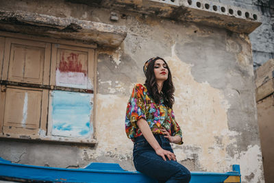 Full length of woman sitting against wall