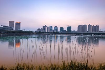 Reflection of buildings in lake against sky during sunset