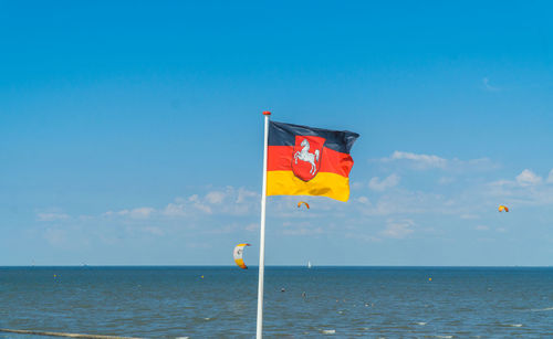 Flag on beach against blue sky
