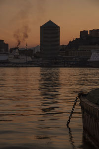 River by buildings against sky during sunset