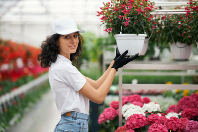 Portrait of young woman standing by flowering plants