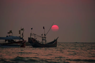 Boat moored in sea against sky during sunset